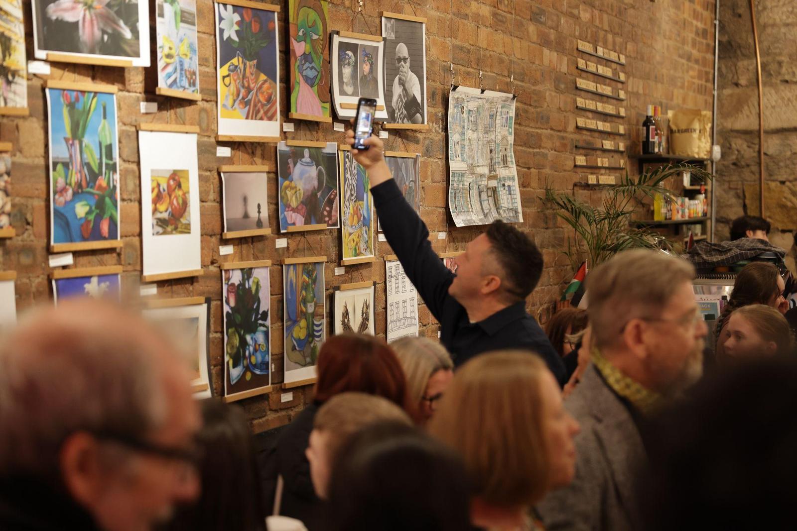 A visitor photographing a pupil's cityscape drawing at the 2024 exhibition.