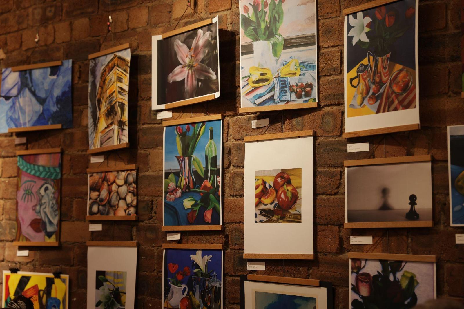 Pupils' paintings and drawings hung on the brick wall at the 2024 exhibition.